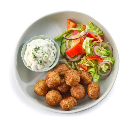plate of meat balls, vegetable salad and greek tzatziki sauce isolated on white background, top view