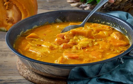 Téléchargez les photos : Potiron et ragoût de carottes dans une casserole sur une table de cuisine rustique. processus de fabrication de soupe à la crème de courge saine - en image libre de droit