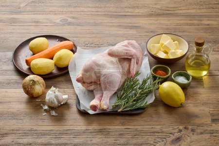 Photo for Chicken roast ingredients on wooden kitchen table - Royalty Free Image