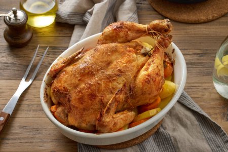 Photo for Roasted chicken and vegetables on wooden kitchen table - Royalty Free Image
