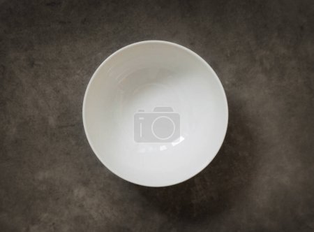 Foto de Cuenco blanco vacío en la mesa de cocina oscura, vista superior - Imagen libre de derechos