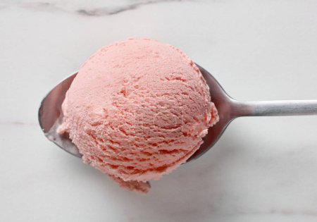 Photo for Pink strawberry ice cream ball in a spoon, top view - Royalty Free Image