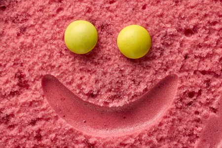 Téléchargez les photos : Drôle sourire visage crème glacée, sorbet framboise et bonbons ronds jaunes, vue de dessus - en image libre de droit