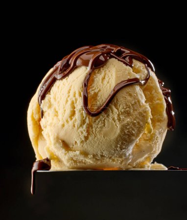 Photo for Melted chocolate on vanilla ice cream ball on black background - Royalty Free Image