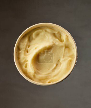 Foto de Open homemade vanilla ice cream container on dark grey background - Imagen libre de derechos