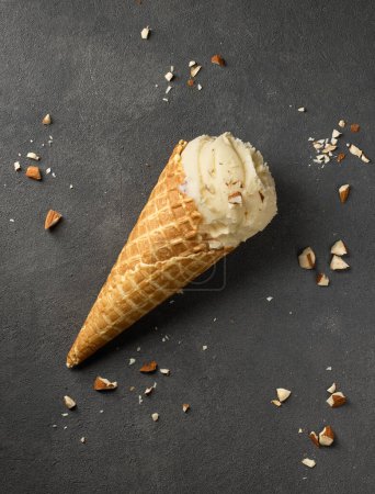 Foto de Vanilla ice cream in waffle cone on dark grey background, top view - Imagen libre de derechos