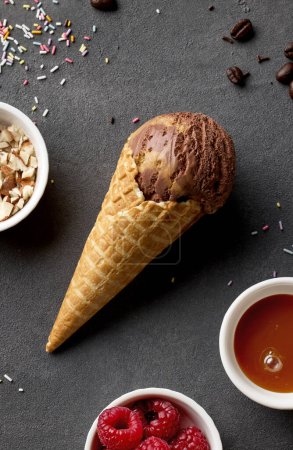 Foto de Caramel and chocolate ice cream in waffle cone on dark grey background, top view - Imagen libre de derechos