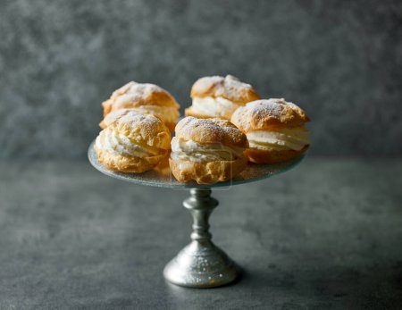 Photo for Plate of cream puffs decorated with powdered sugar on dark grey background - Royalty Free Image