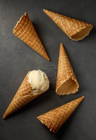 Photo for Vanilla ice cream and waffle cones on dark grey background, top view - Royalty Free Image
