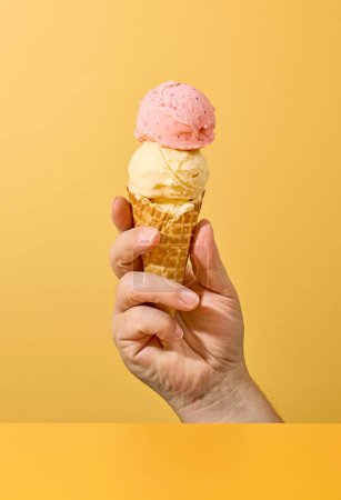 Téléchargez les photos : Ice cream in human hand on yellow background - en image libre de droit