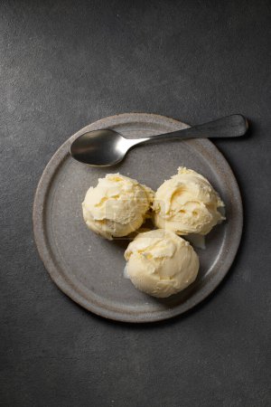 Photo for Plate of vanilla ice cream on black table, top view - Royalty Free Image