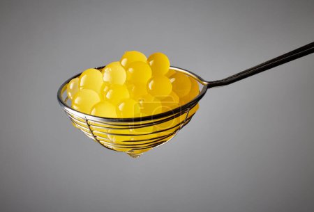 Photo for Yellow jelly balls for making bubble tea in strainer on grey background - Royalty Free Image