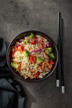 Photo for Bowl of fried rice and vegetables on black table top background - Royalty Free Image