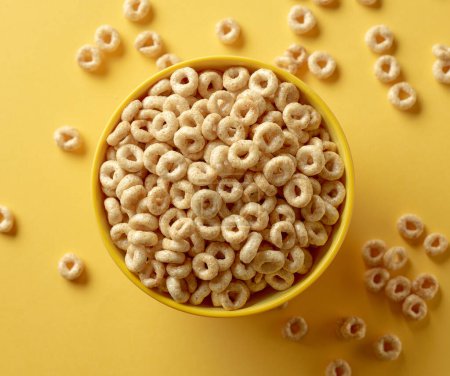 Photo for Bowl of breakfast cereal honey rings isolated on yellow background, top view - Royalty Free Image