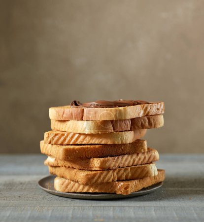 Foto de Stack of toasted bread slices with chocolate cream on kitchen table - Imagen libre de derechos