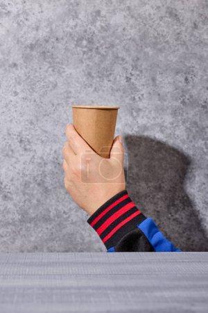 Photo for Take away coffee cup in human hand on grey background, selective focus - Royalty Free Image