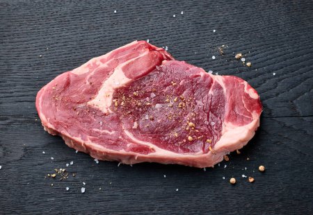 Téléchargez les photos : Steak d'entrecote de bœuf cru frais sur panneau en bois noir, vue de dessus - en image libre de droit