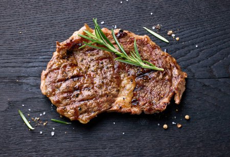 Téléchargez les photos : Steak d'entrecote de bœuf fraîchement grillé sur planche de bois noire, vue de dessus - en image libre de droit