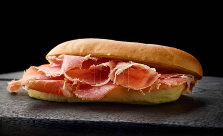 Photo for Sandwich with sliced spanish iberico ham on black wooden board - Royalty Free Image