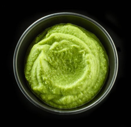Foto de Tazón de puré de verduras verdes aislado sobre fondo negro, vista superior - Imagen libre de derechos