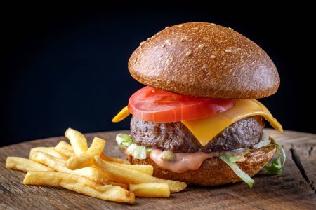 Photo for Fresh tasty burger and french fries on wooden board - Royalty Free Image