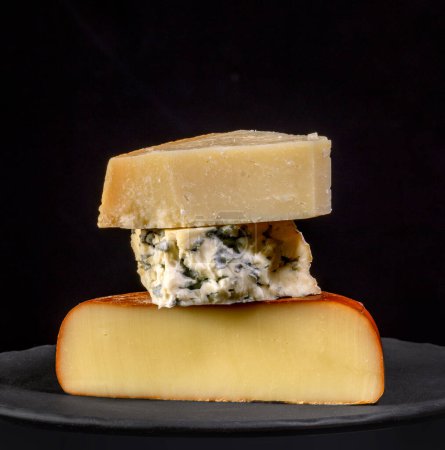 Téléchargez les photos : Pile de différents morceaux de fromage sur fond noir - en image libre de droit