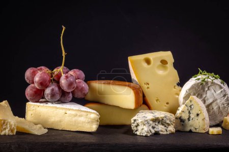 Téléchargez les photos : Nature morte avec divers fromages et raisins sur fond noir - en image libre de droit