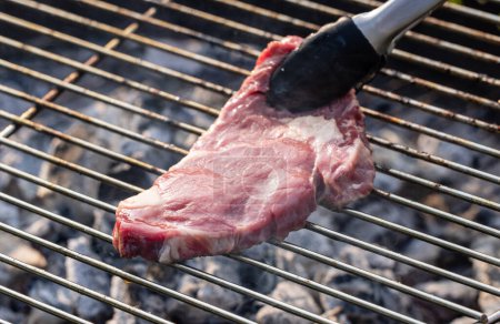 Téléchargez les photos : Grillade de steak de bœuf cru frais sur barbecue au charbon de bois - en image libre de droit