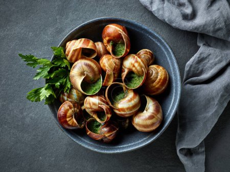 Photo for Bowl of escargot snail filled with garlic and parsley butter on grey background, top view - Royalty Free Image