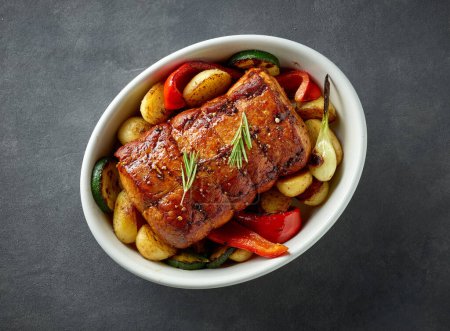 Foto de Tazón de cerdo asado entero y verduras en la mesa de cocina gris oscuro, vista superior - Imagen libre de derechos