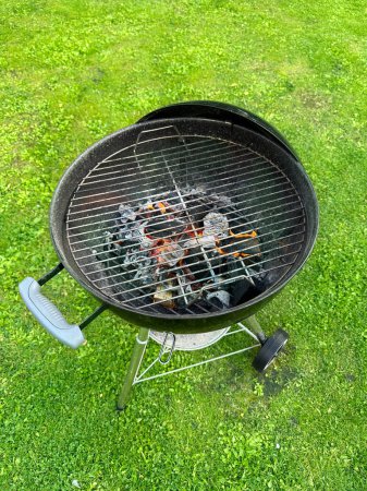 Téléchargez les photos : Grille de charbon de bois à combustion ouverte sur fond d'herbe verte - en image libre de droit
