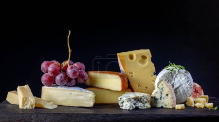 Stillleben mit verschiedenen Käsesorten auf schwarzem Hintergrund