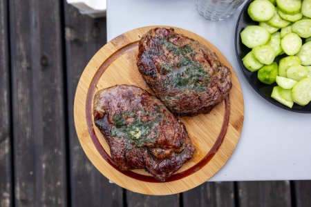 Photo for Freshly grilled juicy beef steaks on wooden cutting board, top view - Royalty Free Image