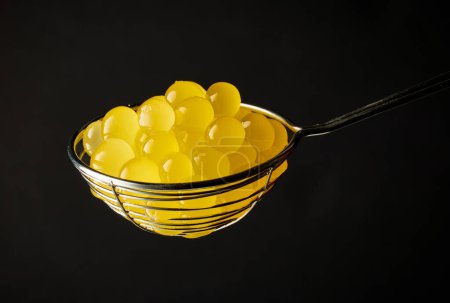 Foto de Bolas de gelatina amarilla para hacer té de burbuja en colador sobre fondo negro - Imagen libre de derechos