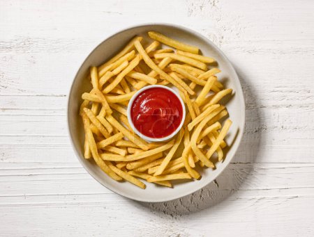 Foto de Papas fritas con salsa de tomate sobre mesa de madera blanca, vista superior - Imagen libre de derechos