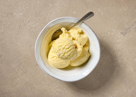 Téléchargez les photos : Gros plan du bol de crème glacée vanille sur la table de couleur beige, vue du dessus - en image libre de droit