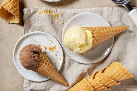 Photo for Chocolate and vanilla ice cream in waffle cones on plates, top view - Royalty Free Image