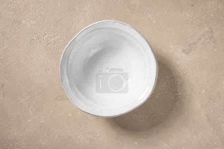 Foto de Cuenco blanco vacío sobre fondo de color beige, vista superior - Imagen libre de derechos
