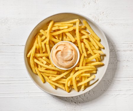 Foto de Tazón de papas fritas y salsa de mayonesa en la mesa de madera blanca, vista superior - Imagen libre de derechos