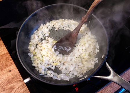 Téléchargez les photos : Oignons hachés friture dans la poêle sur la cuisinière dans la cuisine domestique, vue sur le dessus, mise au point sélective - en image libre de droit