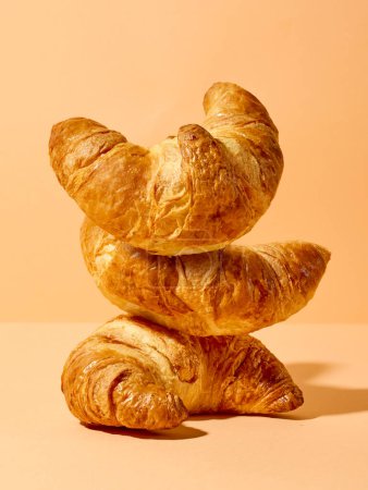 Téléchargez les photos : Pile de croissants fraîchement cuits sur fond de couleur orange - en image libre de droit