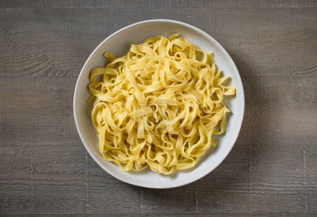 Photo for Bowl of pasta on kitchen table, top view - Royalty Free Image