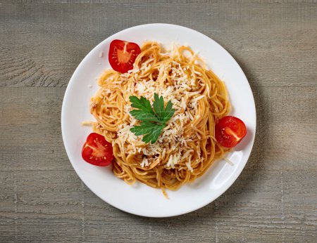 Photo for Plate of spaghetti with bolognese sauce and tomatoes on wooden kitchen table, top view - Royalty Free Image