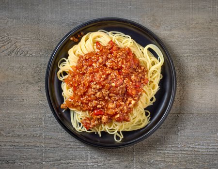 Photo for Plate of pasta spaghetti with sauce bolognese on wooden kitchen table, top view - Royalty Free Image