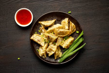 Photo for Plate of asian dumplings on dark wooden table, top view - Royalty Free Image