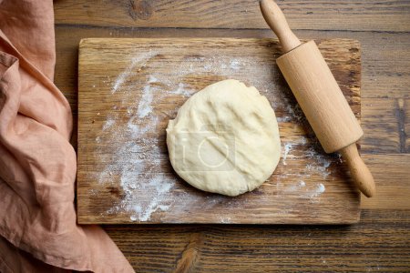 Photo for Fresh yeast dough and rolling pin on wooden kitchen table, top view - Royalty Free Image