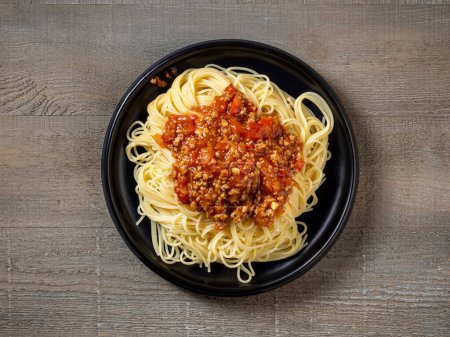 Photo for Plate of spaghetti bolognese on old wooden kitchen table, top view - Royalty Free Image