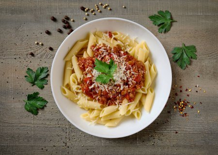 Photo for Plate of pasta bolognese on old wooden kitchen table, top view - Royalty Free Image