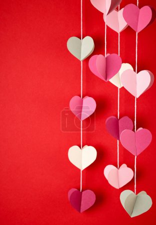 Photo for Heart shaped colorful paper decorations hanging on red background - Royalty Free Image