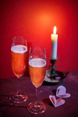 Foto de Dos copas de champán y una vela encendida sobre fondo rojo - Imagen libre de derechos